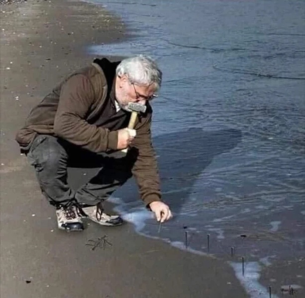 Guy Hammering Nails Into Sand blank meme template